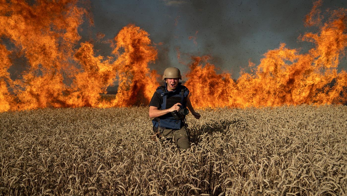 TIL NORGE: Fotojournalist Evgeniy Maloletka på flukt fra en brann i en hveteåker etter et russisk angrep ved den ukrainsk-russiske grensen i Kharkiv, Ukraina 29. juli i 2022. July 29. 2022. Fotografiet er tatt av fotojournalisten Mstyslav Chernov. Begge har vunnet Free Media Awards og kommer til Oslofor å ta den imot.