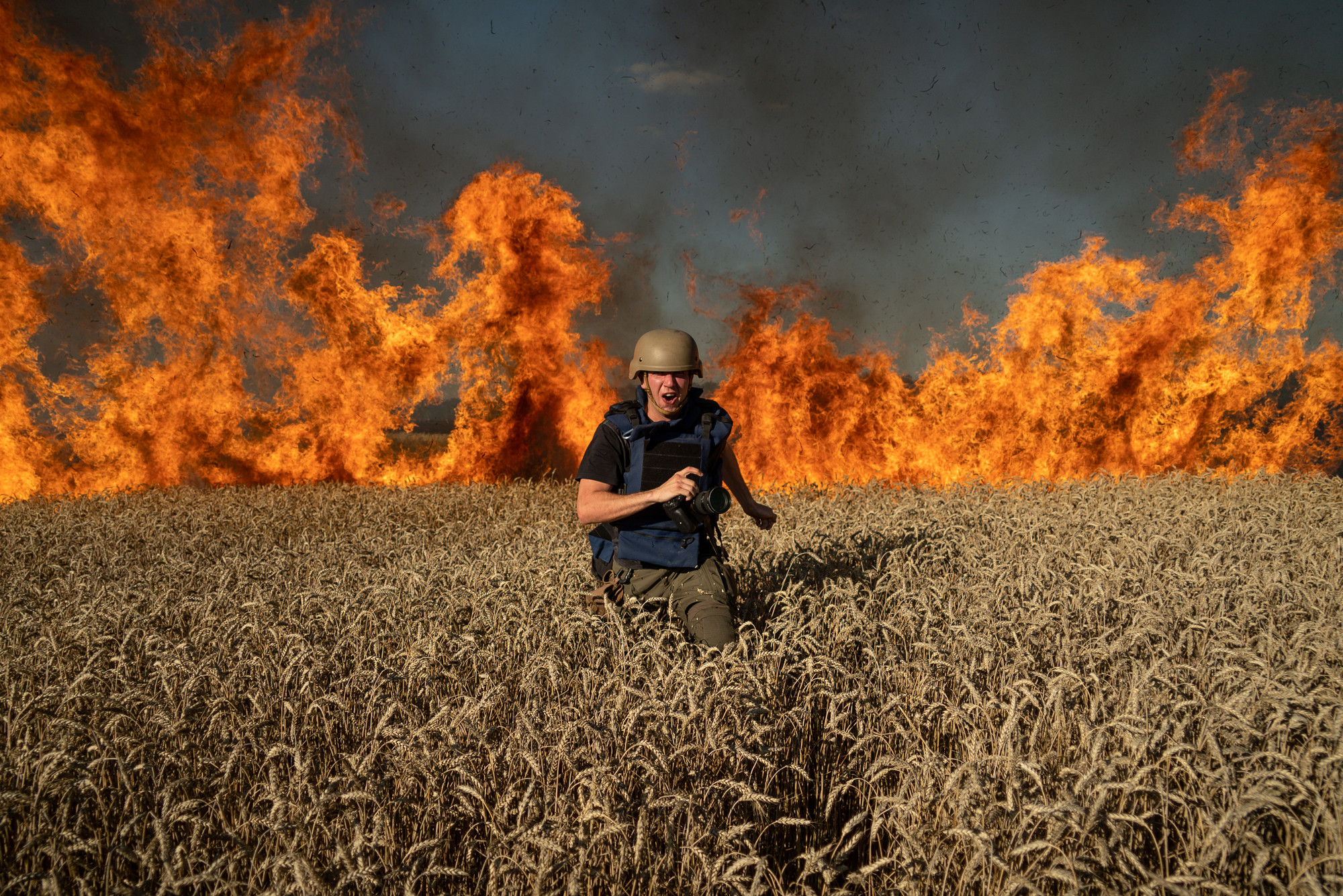 TIL NORGE: Fotojournalist Evgeniy Maloletka på flukt fra en brann i en hveteåker etter et russisk angrep ved den ukrainsk-russiske grensen i Kharkiv, Ukraina 29. juli i 2022. July 29. 2022. Fotografiet er tatt av fotojournalisten Mstyslav Chernov. Begge har vunnet Free Media Awards og kommer til Oslofor å ta den imot.